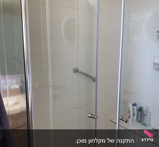 מקלחון זכוכית עם מוצרים על מדף